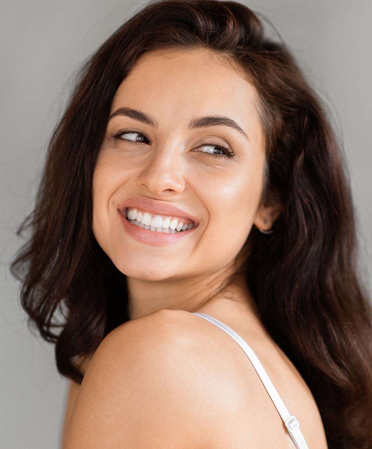 Smiling woman with brown hair and radiant skin.