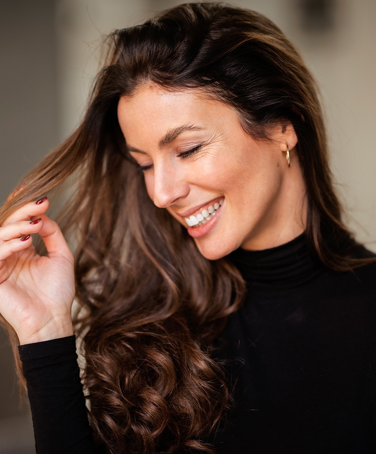 Woman smiling with wavy hair in black outfit.