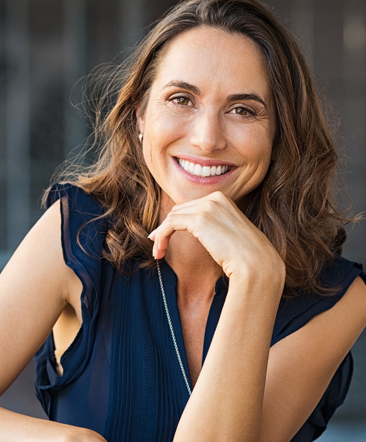 Smiling woman with brown hair resting her chin.