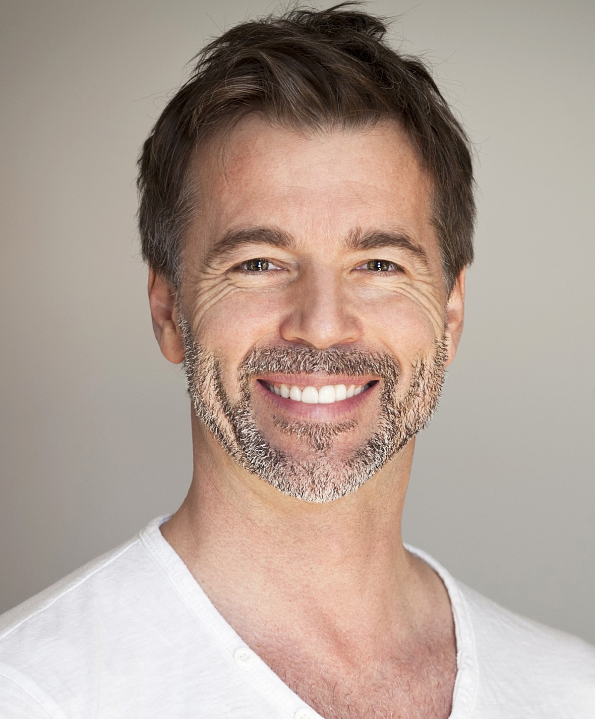 Smiling man with beard in casual attire.