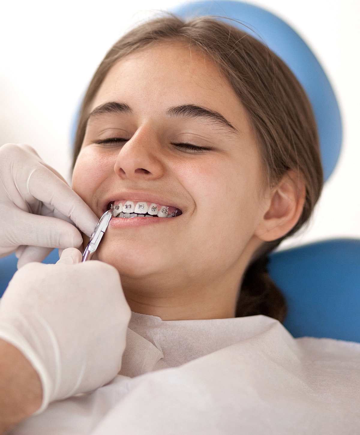 Teen girl getting braces adjusted at dentist.